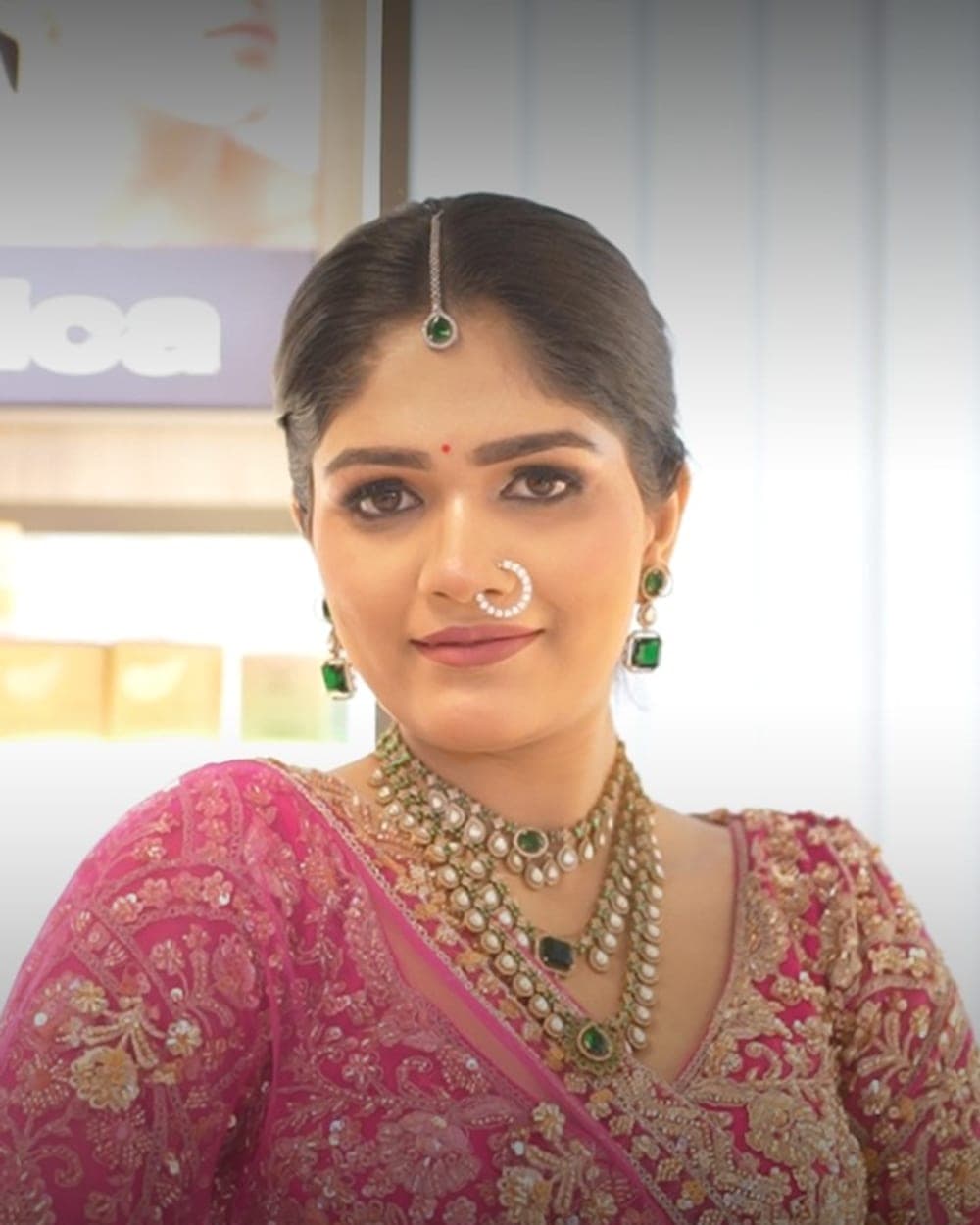 Bridal client at Lakmé Salon Rajajipuram in a pink and gold lehenga with kundan and emerald jewellery